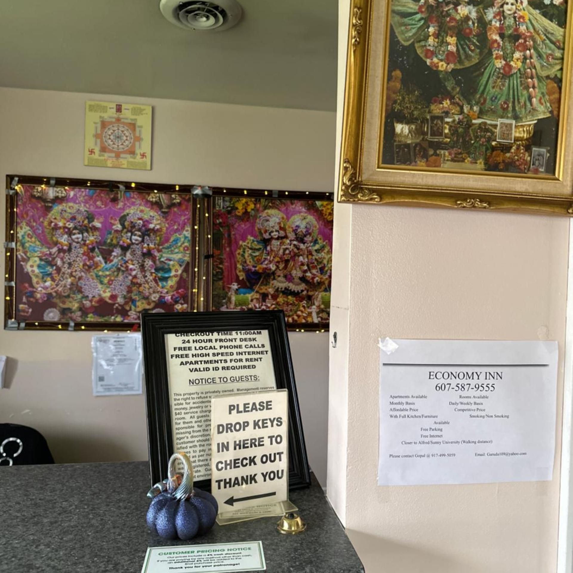 A hotel reception area with a framed artwork, a notice board with a message, and a sign for Economy Inn.