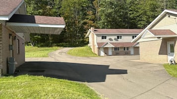 A residential property with a paved driveway, a covered porch, and a two-story house with a brick facade.