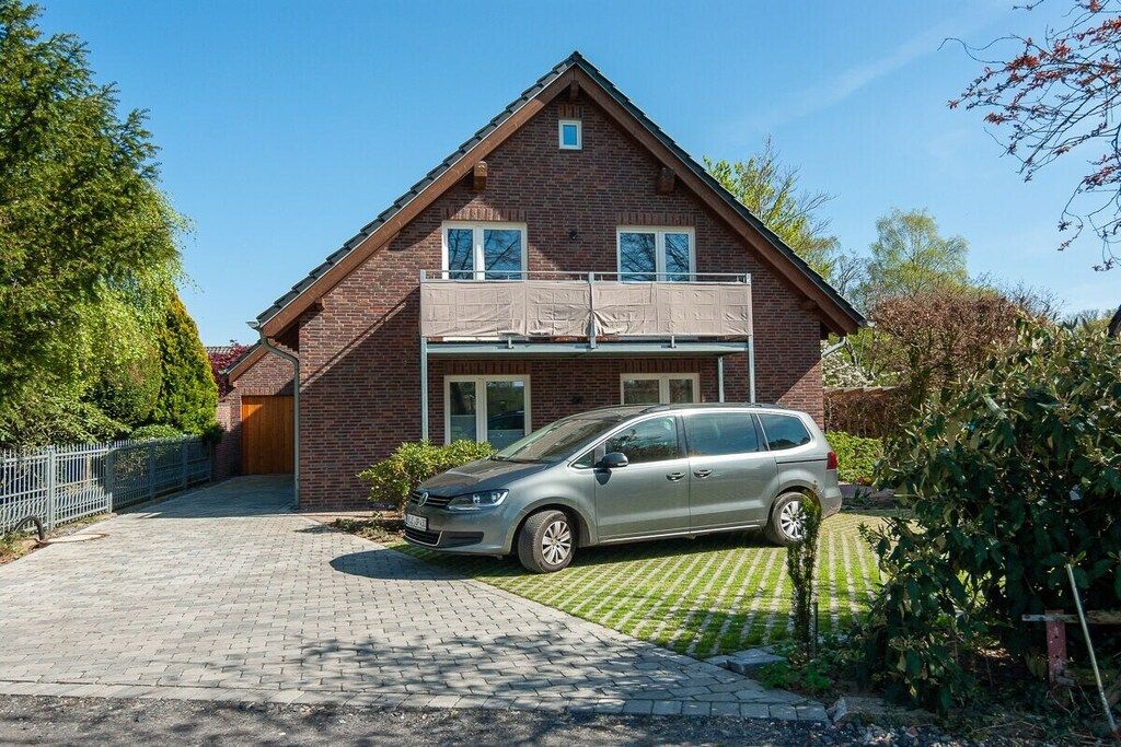 A two-story brick house with a car parked in the driveway.