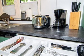 A kitchen counter with a coffee maker, a kettle, and a knife block. - Garden (Holiday home Haldern) (Rees)