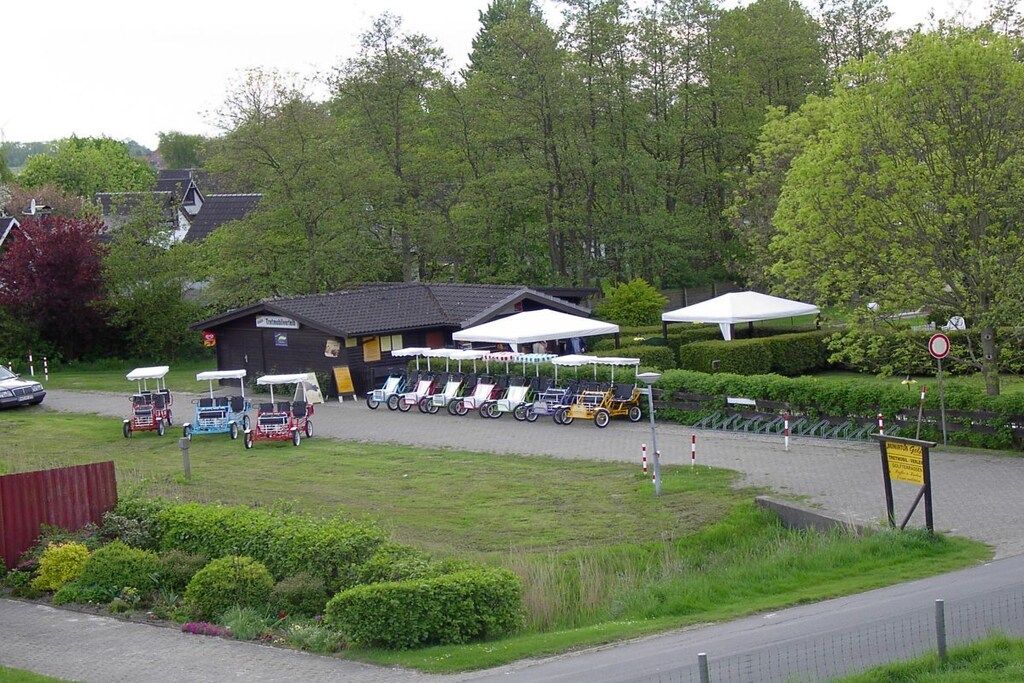 A golf course with a clubhouse, multiple golf carts, and a parking area.