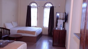Una habitación de hotel con cama, escritorio, silla, una mesita y espejo.