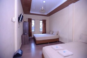 Ein Hotelzimmer mit Bett, Fernseher, Kleiderschrank und einem fenster mit Vorhängen.