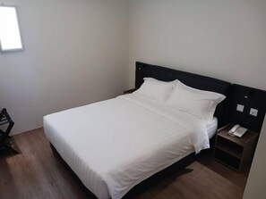 A single bed with a white mattress and pillows, a bedside table with a phone, and a wall-mounted light fixture. - Soho Tabuan Hotel Kuching (Kuching)