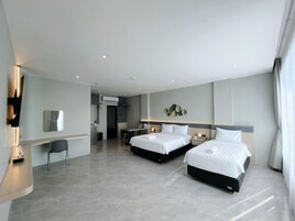 A modern hotel room with two beds, a desk, and a seating area.