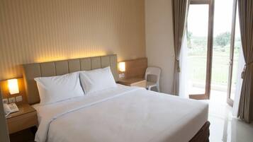 A hotel room with a large bed, bedside lamps, a chair, and a view of the outdoors.