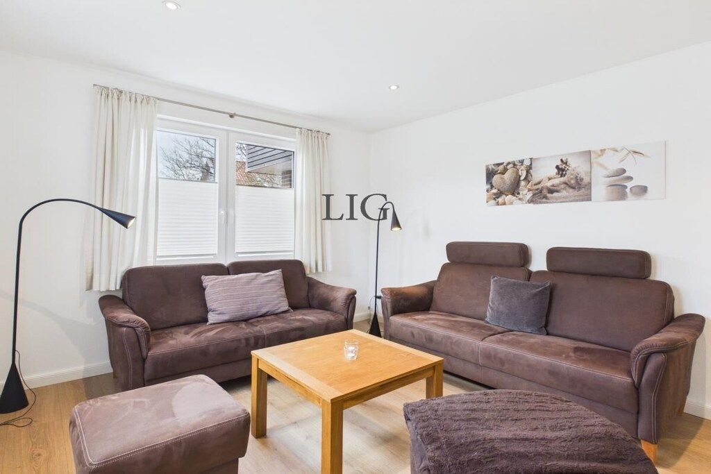 A modern living room with two brown leather sofas, a wooden coffee table, and a floor lamp.
