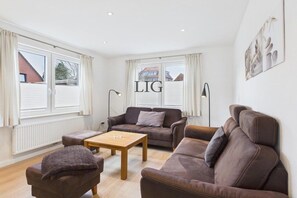 A living room with a brown sofa set, a wooden coffee table, and a lamp. - Holiday apartment Otten 1 (Langeoog)