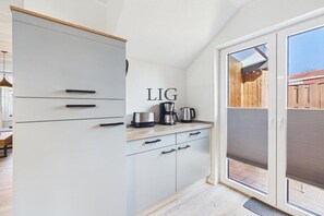 A kitchen with a sliding glass door leading to an outdoor area. - Holiday apartment Salzwiese (Langeoog)