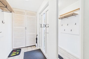 A hallway with a double door, a coat rack, and a black umbrella. - Holiday apartment Salzwiese (Langeoog)