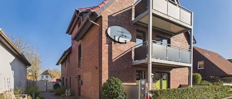 Un bâtiment à deux étages, doté d’une antenne parabolique, d’une entrée fermée par un portail et d’une allée pavée.
