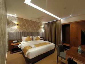 Ein Hotelzimmer mit einem großen Bett, einem Schreibtisch, einem Stuhl, einem Kleiderschrank und einem Deckenventilator.