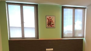A room with two beds, a headboard, a window with a view, and a wall-mounted light switch. - Viva Hotel SRI Aman (Sri Aman)