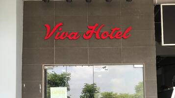 The entrance to Viva Hotel with a glass door, a welcome mat, and a red chair outside.