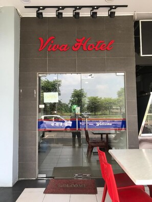 The entrance to Viva Hotel with a glass door, a welcome mat, and a red chair outside. - Viva Hotel SRI Aman (Sri Aman)