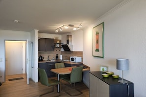 A compact kitchen with a dining area, a microwave, and a small cabinet with bowls. - Holiday apartment with 1 bedroom (Cuxhaven-Döse)