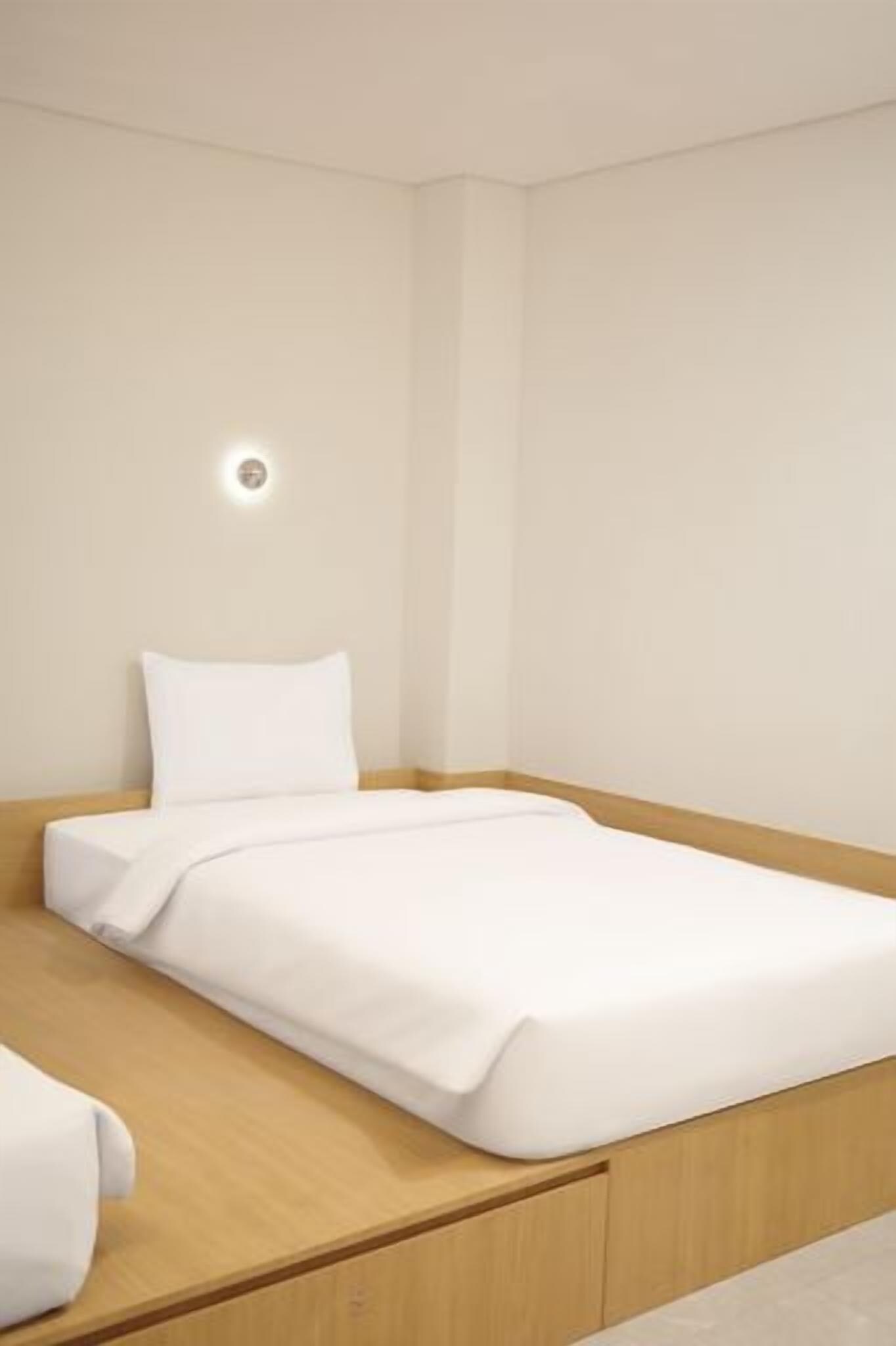 A single bed with a wooden headboard, a white mattress, and a white pillow.