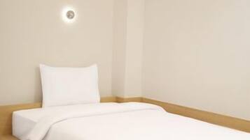 A single bed with a wooden headboard, a white mattress, and a white pillow.