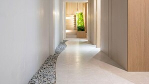 Corredor moderno com caminho de pedras, piso de madeira e vista para escadaria que leva a um quarto com parede verde.