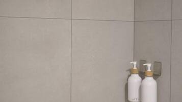 A tiled shower wall with two bottles of shampoo and conditioner.