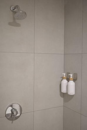 Eine mit Fliesen verkleidete Duschwand mit zwei Shampoo- und Conditionerflaschen.
