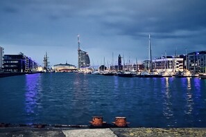 A waterfront marina with boats docked, a prominent building with a spire, and a large dome structure. - Holiday home in Wanna with Wi-Fi and parking (Wanna)