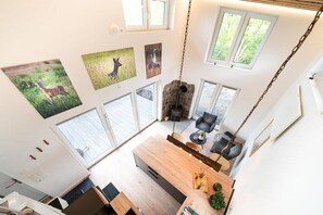 A high-ceilinged room with a wooden dining table, a hanging light fixture, and a stone fireplace. - Holiday home in Wanna with Wi-Fi and parking (Wanna)