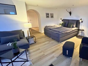 A modern living room with a sofa, a bed, a small table, and a lamp. - Apartment Eifelgluck With Roof Terrace (Pelm)