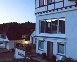 A two-story building with a balcony and a staircase leading to the entrance. - Apartment Eifelgluck With Roof Terrace (Pelm)