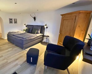 Ein Schlafzimmer mit einem Bett, Nachttischlampen, einem Holzschrank, einem kleinen Tisch und einem Stuhl.