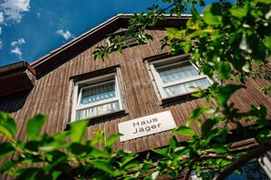 Ein Holzhaus mit einem Schild, auf dem 'Haus Jäger' steht, und zwei Fenstern.