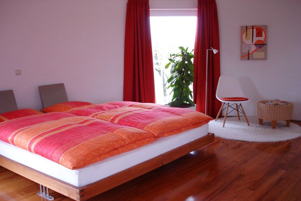 Un dormitorio con una cama grande, una planta en maceta, una silla y una lámpara.