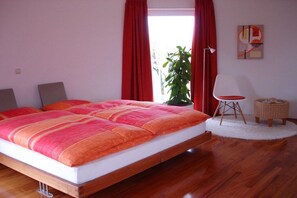 Een slaapkamer met een groot bed, een potplant, een stoel en een lamp.