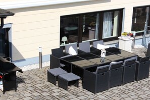 Eine Außenpatio mit Tisch und Stühlen, einem Grill und einem Fenster mit Vorhängen.