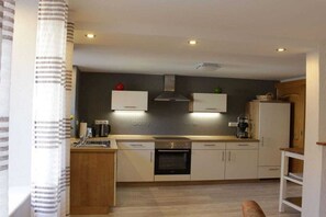 Eine kleine Küche mit weißen Schränken, einem eingebauten Backofen und einer Kaffeemaschine.