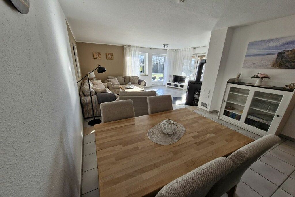 A spacious living area with a wooden dining table, sofas, and a television.
