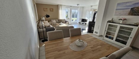 Un amplio salón con una mesa de comedor de madera, sofás y una televisión.
