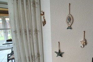 A room with a white curtain, a table, and wall-mounted decorations including a fish, a starfish, and a bird. - Holiday apartment with 2 bedrooms (Wenkendorf)