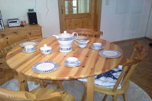 A wooden dining table with matching plates, a teapot, and cups. - Lüttje Huus an d" Kark (Krummhörn)
