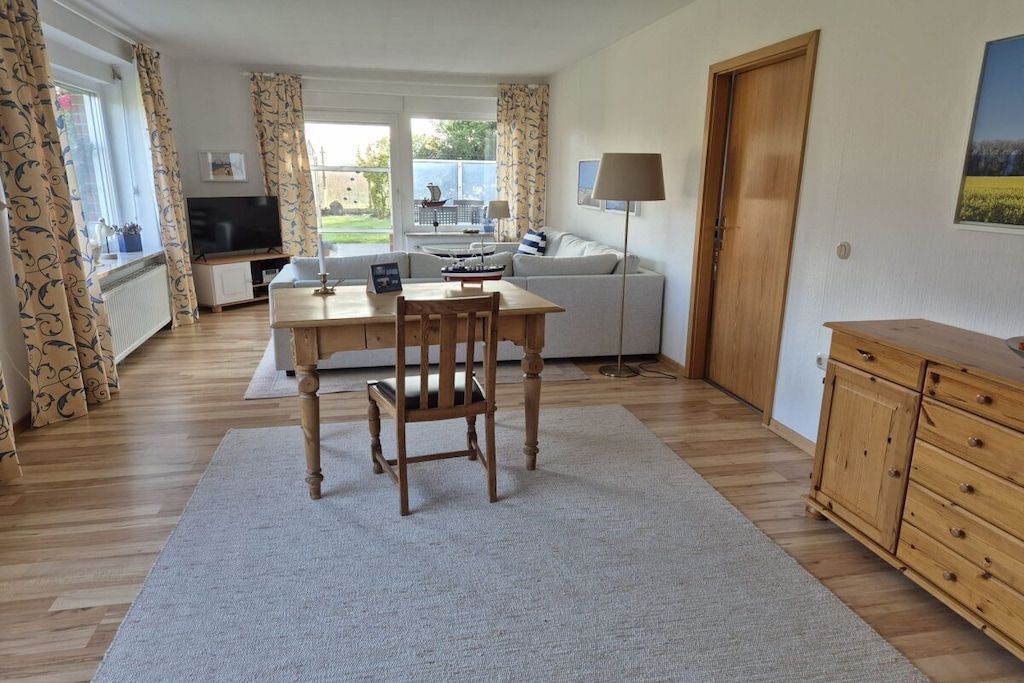 A room with a dining table, chairs, a sofa, a TV, and a lamp.