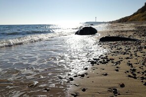 A beach with waves, pebbles, and a distant tower. - Holiday apartment with 2 bedrooms (Fehmarn)