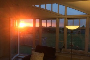 Een kamer met een groot raam, een stoel en een lamp.