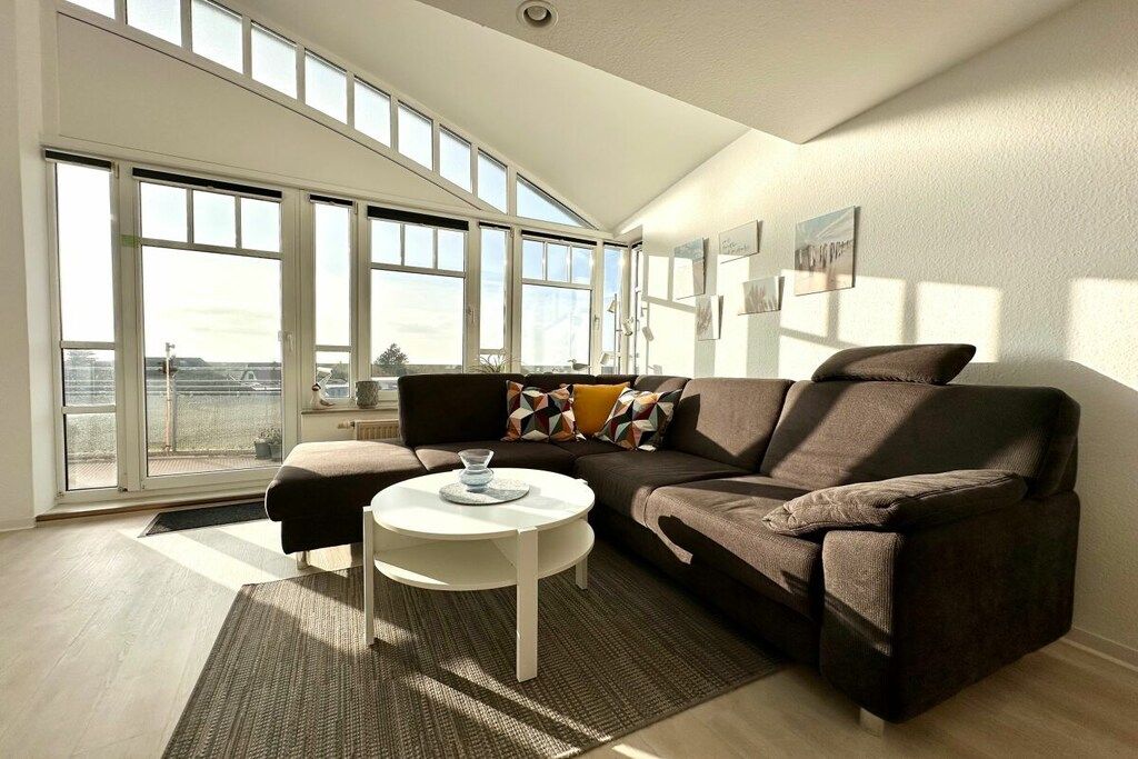 A modern living room with a sofa, a coffee table, and large windows.