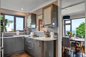 Eine moderne Küche mit grauen Schränken, einem eingebauten Backofen und einem Essbereich mit Tisch und Stühlen.