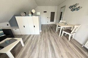Ein kompakter Wohnbereich mit Küchenzeile, einem Essbereich mit Tisch und Stühlen sowie einer Sitzecke mit Sofa und Couchtisch.