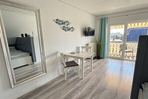 Een kamer met een bed, een tafel met stoelen, een televisie en een balkon met uitzicht op gebouwen.
