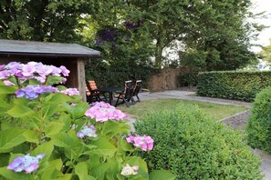 A garden with a wooden structure, a table with chairs, and a hedge. - Friesenkoje Horumersiel - bunk 3 (Wangerland)