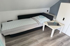Ein kleines Schlafzimmer mit einem Bett, einem Nachttisch und einem Kleiderschrank.