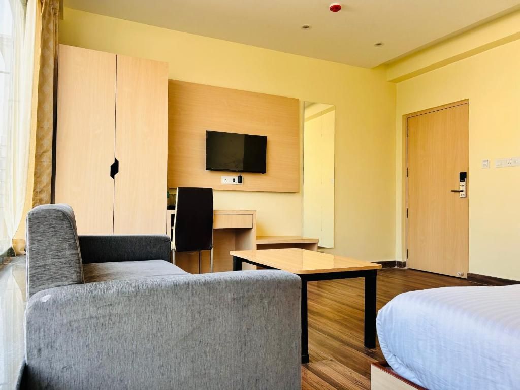 Habitación de hotel con cama, escritorio, silla, televisión y armario.