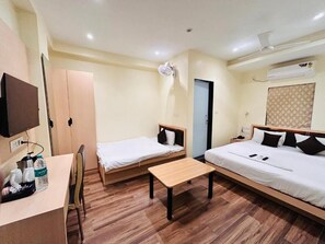 A hotel room with two beds, a desk, and a chair. - Hotel Golden Square (Kolkata)